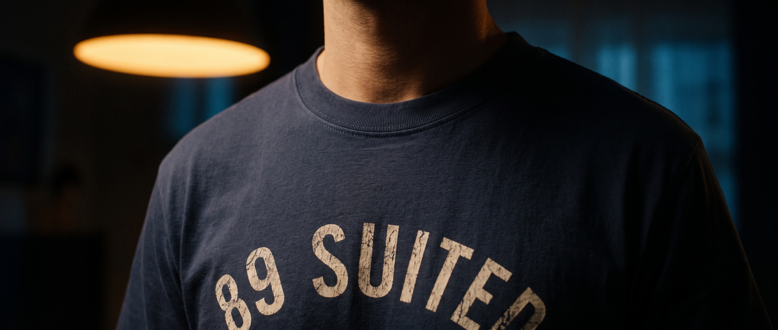 A player wearing the navy 89 Suited tee under a hanging card room lamp