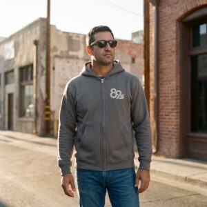 The Night Session Zip hoodie in asphalt, worn zipped, with the 89s monogram on the left chest.